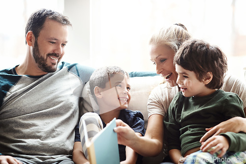 Image of Mother, father and kids on sofa for storytelling time in living room of happy family home. Love, books and couple with children smile, book and fantasy story time on couch, growth and development.