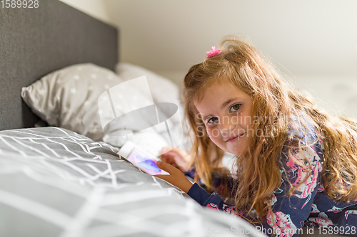 Image of Little Girl watching movie On A Digital Tablet