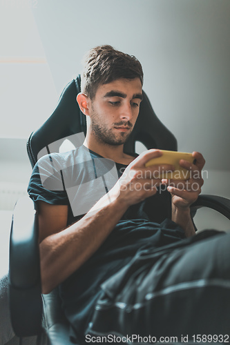 Image of casual man holding and using smartphone