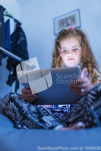 Image of Little Girl watching movie On A Digital Tablet