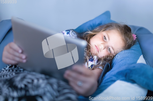 Image of Little Girl watching movie On A Digital Tablet