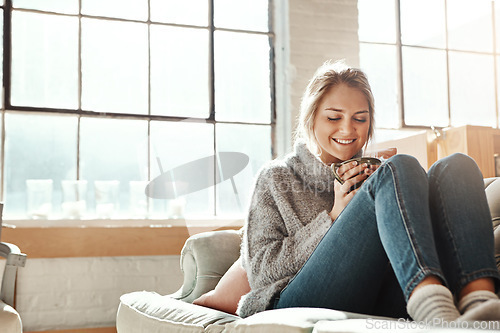 Image of Woman on sofa, coffee and relax for happiness, break and on weekend for solitude, home and living room. Young female, girl or tea in lounge on couch, comfortable or smile with drink, house and casual