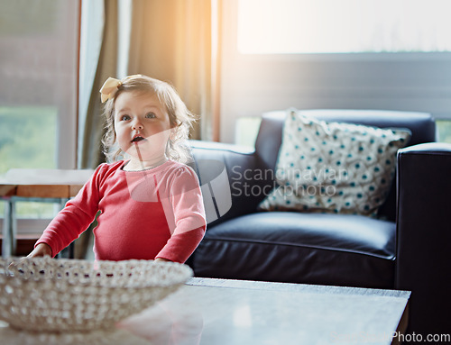 Image of Children, baby and a girl in the living room of her home with mockup or flare looking curious while standing alone. Kids, development and lifestyle with a cute female child in a house during the day