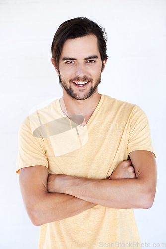 Image of Happy, smile and portrait of a man with casual fashion and tshirt with vertical white background. Isolated, arms crossed and model smiling and feeling positive with joy alone looking comfortable