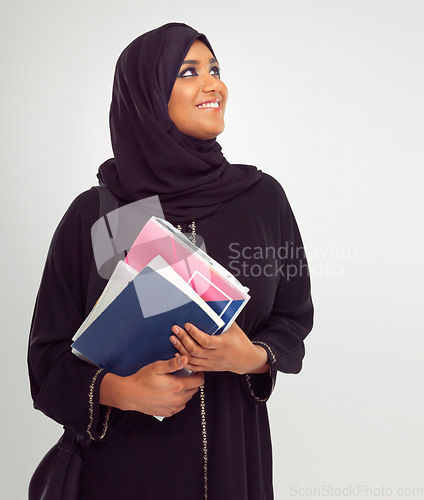 Image of Muslim, student and thinking with an islamic girl holding books in studio on a gray background for education. Idea, learning and islam with a female pupil on a scholarship to study at university