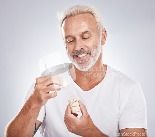 Image of Skincare, health and senior man with face serum in a studio for a wellness, cosmetic and natural face routine. Cosmetics, beauty and elderly guy with facial oil for skin treatment by gray background.