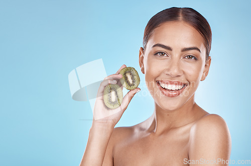 Image of Skincare, kiwi and portrait of beauty woman with natural smile and healthy glow for marketing. Wellness, happy and self care model with fruit for cosmetic advertising in blue studio mockup.