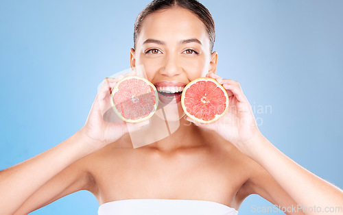 Image of Woman, studio portrait and grapefruit for skincare, natural cosmetic or health by blue background. Model, fruit and smile for nutrition, vitamin c or self care beauty for aesthetic by studio backdrop