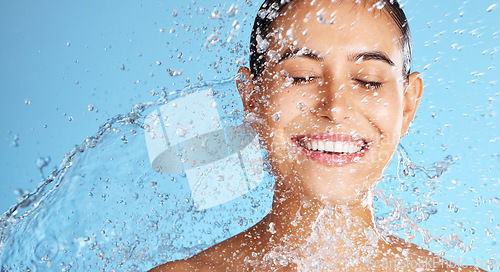 Image of Water splash, smile and skincare, woman with mockup and product placement on clean blue background. Dermatology, fresh and happy person cleaning face with marketing for luxury anti ageing cosmetics.