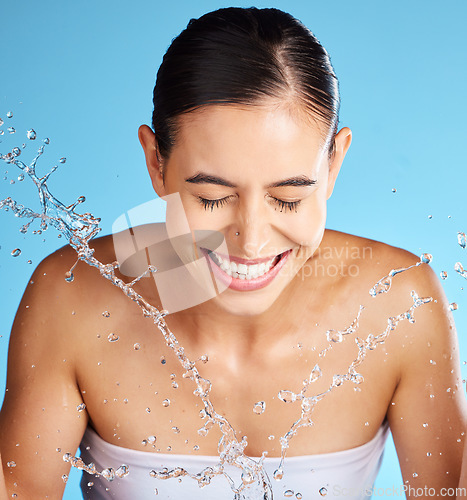 Image of Face wash, skincare and woman isolated on blue background for beauty, cosmetics cleaning and happy. Smile of a person or model with water splash for dermatology wellness and aesthetic in studio