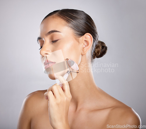 Image of Rose quartz, face roller and woman skincare of a model relax from facial spa treatment. Isolated, studio background and young person busy with dermatology, self care and beauty treatment for skin