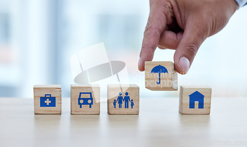 Image of Hands, wooden blocks and building on table for essential fundamentals or safe foundation lifestyle. Hand of person putting small wood block, object or icons together of umbrella to build row on desk