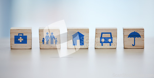 Image of Medical, house and life insurance on blocks background for family clinic, safety and healthcare icon or sign. Future goals, risk management and car or home cover with umbrella on wood for services