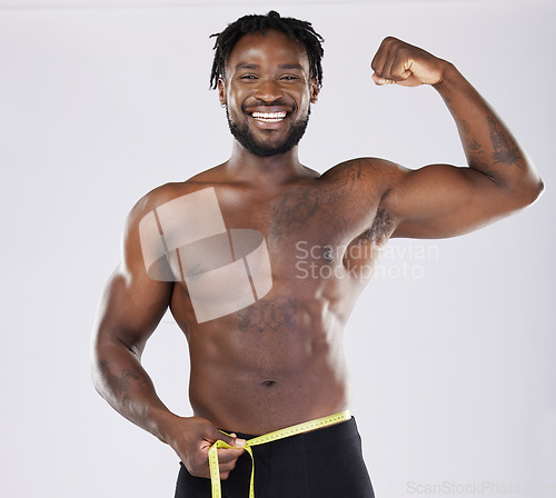 Image of Muscular black man, tape measure and flexing in fitness for weight loss or dieting isolated on a grey background. Portrait of happy sporty male with smile for healthy lifestyle, fit body or muscle