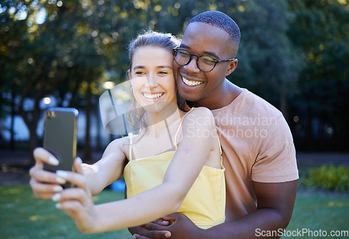 Image of Selfie, phone and interracial couple hug in park enjoying weekend, summer holiday and quality time together. Nature, dating and happy man and woman take picture on smartphone relax, calm and freedom