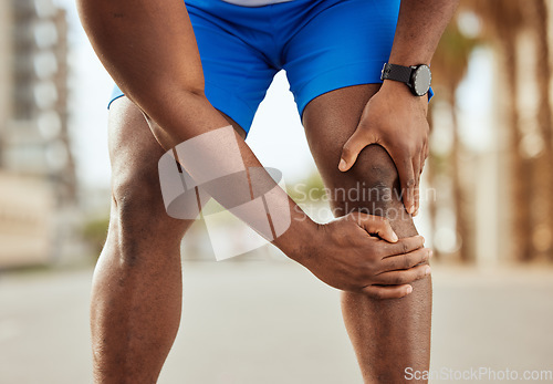 Image of Fitness, pain in knee and hands of black man with muscle ache, joint pain and injury after running in city. Sports, body wellness and male athlete rest after workout, marathon training and exercise