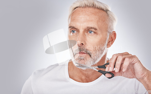 Image of Facial hair, cutting and man with scissors for grooming, shaping and routine treatment on a studio background. Barber, cleaning and face of a senior model trimming beard during morning clean