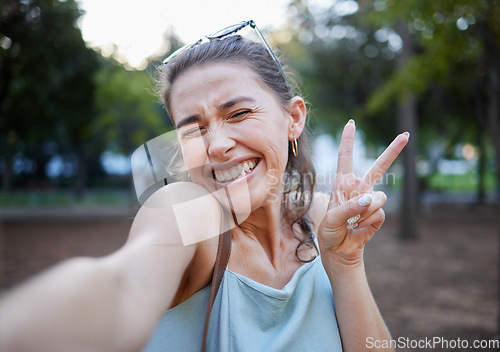 Image of Selfie, peace and face with a woman in a park, posing for a photograph alone outdoor in nature. Social media, emoji and hand sign with an attractive young female alone outside in a garden or field