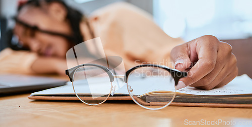 Image of Black woman, glasses and sleeping in home office with a book while studying or working with fatigue. Entrepreneur person tired, burnout and exhausted with remote work and startup business stress