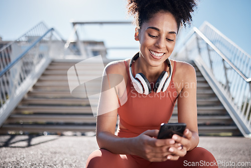 Image of Fitness, phone and black woman in city on break on social media, texting or web browsing after exercise. Sports, cellphone and happy female athlete by stairs with 5g mobile smartphone for networking.