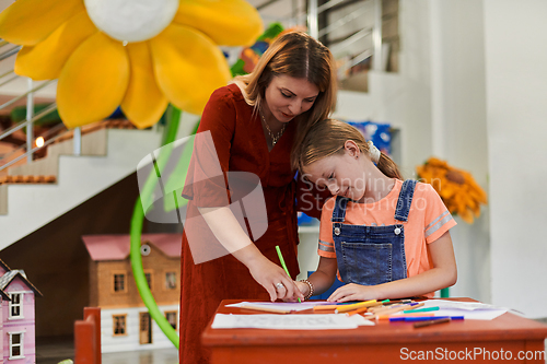 Image of Creative kids during an art class in a daycare center or elementary school classroom drawing with female teacher.