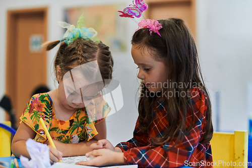 Image of Creative kids sitting in a preschool institution, draw and have fun while they get an education