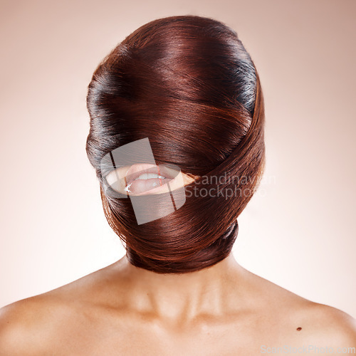 Image of Head, haircare and salon with a model woman in studio on a pink background wrapped in her own hair. Beauty, hairdresser or keratin treatment with a young female wrapping her hairstyle around her face