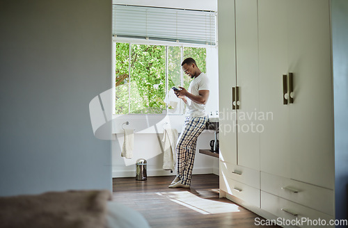 Image of Phone, bathroom and black man in home on social media, texting or internet browsing. Relax, cellphone or happy male holding mobile smartphone for web scrolling, networking or messaging alone in house