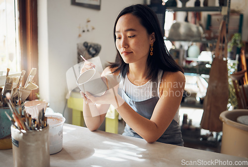 Image of Pottery, art and sculpture with a japanese woman in a studio for design or a creative hobby as an artisan. Manufacturing, pattern or artist with a female potter sitting in her workshop as a sculptor