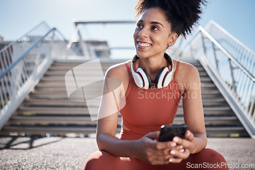 Image of Fitness, headphones and smartphone with woman on stairs thinking of workout, exercise or training website, blog or social media. Mental health technology, sports music and happy black woman in city
