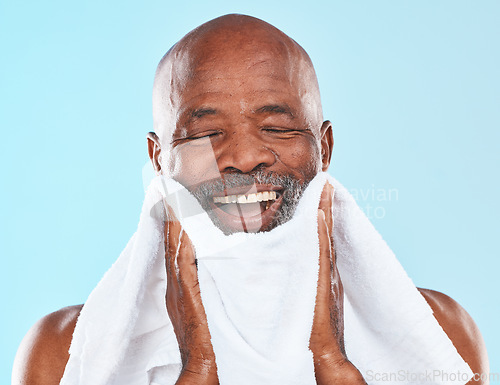 Image of Black man, studio and towel for shave, smile and wellness for self care, hygiene and beard by blue background. Senior man, happy and cloth for skincare, wellness and grooming routine by backdrop