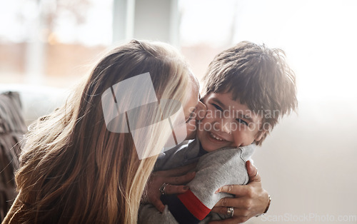 Image of Family, children and love with a mother kissing her son in the living room of their home while bonding together. Kids, kiss and smile with a woman hugging her boy child on the cheek in a house