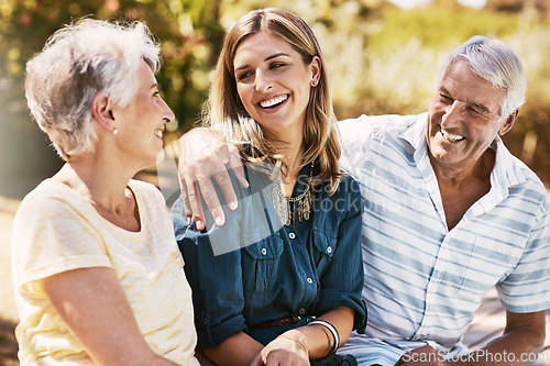 Image of Senior parents in nature with their adult daughter sitting, talking and bonding together in a garden. Happy, love and elderly people embracing child with care, happiness and affection in outdoor park