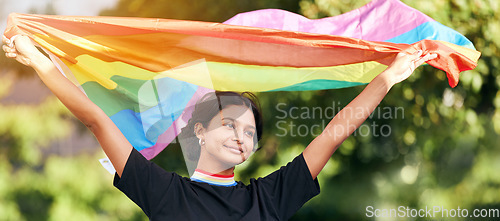 Image of Rainbow, flag and gay pride with an indian woman in celebration of lgbt human rights alone outdoor. Freedom, equality and lgbtq with a happy female outside celebrating her equality or inclusion