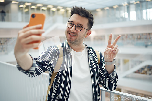 Image of College student, man and library selfie at campus with phone, peace hand and smile on social media. Gen z, university student and smartphone app for social network, happiness and studying for success