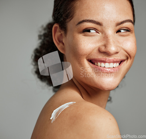 Image of Face, skincare and woman with back cream in studio isolated on gray background. Beauty cosmetics, thinking and happy young female model with lotion, creme or moisturizer for healthy skin or wellness