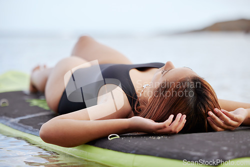 Image of Relax, woman or surfer on water at a beach on holiday vacation resting on a surfboard in Bali. Freedom, thinking or healthy sports girl relaxing body in calm nature, sea or peaceful ocean in summer