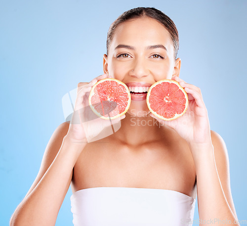 Image of Skincare, beauty and portrait of a woman with grapefruit for a natural, organic and healthy face routine. Cosmetic, wellness and girl model from Mexico with a tropical citrus fruit by blue background