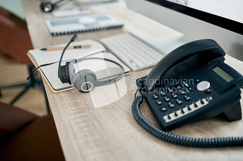 Image of Telemarketing office, phone and VOIP on desk for communication, contact us and consulting by computer. Modern office, telephone and headphones on table for customer support, help or service with pc