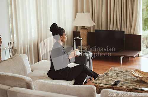 Image of Travel, coffee and business woman in a bedroom relaxing, thinking and drinking a cup of caffeine. Career, luggage and professional corporate female sitting in hotel enjoying a warm drink on work trip