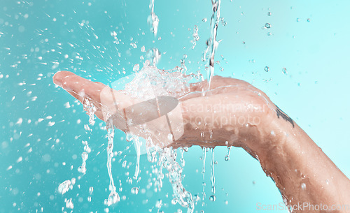 Image of Beauty, cleaning and hand of man with water splash for self care, wellness and cosmetic campaign. Health, hygiene and shower skincare hydration model washing zoom in blue studio background.