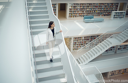 Image of Woman, staircase and walking in the library for education, learning or knowledge from books in the mall. Female having a walk down stairs in big book shop or store for reading or development indoors