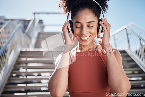 Image of Fitness, music headphones and black woman in city streaming radio or podcast. Face, sports meditation and happy female athlete listening to song or audio outdoors by stairs after training or workout