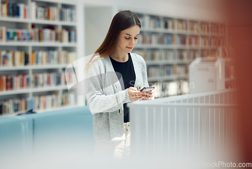 Image of Library, phone and woman student networking on social media, mobile app or internet in college. Bookstore, knowledge and young female typing or reading a text message on her cellphone at university.