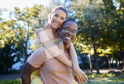 Image of Interracial couple, love and portrait of people with support, care and smile on a summer park adventure. Piggyback, hug and young man and woman outdoor on date together happy about bonding in nature