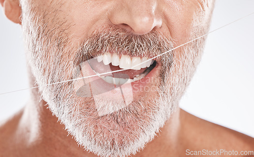 Image of Floss, dental and face of senior man in studio isolated on a gray background. Cleaning, hygiene and elderly male model with product flossing teeth for oral wellness, tooth care and healthy mouth.