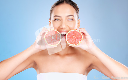 Image of Woman, studio portrait and grapefruit for skincare, natural cosmetic or health by blue background. Model, fruit and smile for nutrition, vitamin c or self care beauty for aesthetic by studio backdrop