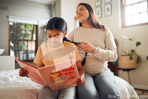 Image of Family, book or education and a girl reading in a bedroom with her mom playing with her hair in their home. Books, learning and love with a mother and daughter bonding while sitting on a bed together