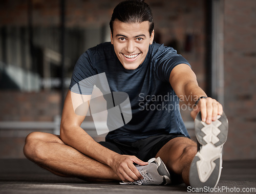 Image of Portrait, fitness and stretching with a man athlete in gym getting ready for his workout routine. Exercise, health and warm up with a handsome young male training in a performance center for wellness