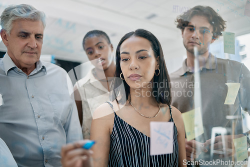 Image of Innovation, meeting or woman writing on a sticky note planning a startup project on glass board in office building. Focus, leadership or creative business people working on strategy ideas or solution